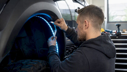 Hands installing LED strip in vehicle wheel well