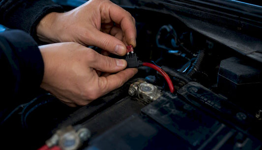 Hands installing automotive blade fuse close-up