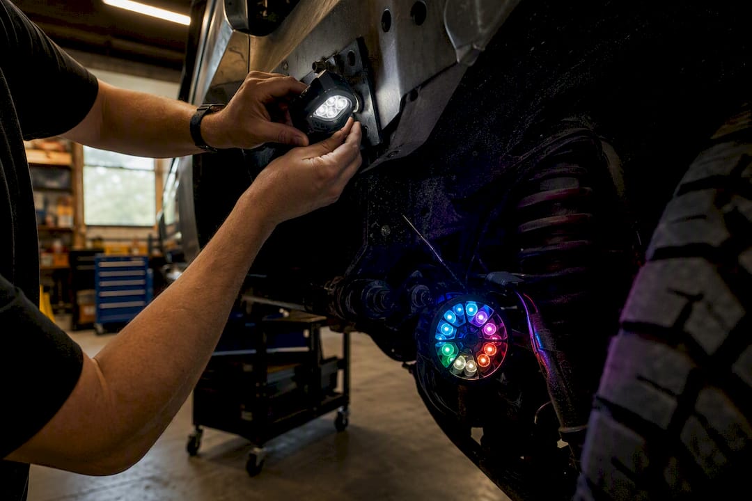 Hands installing rock and portal LED lights on vehicle frame