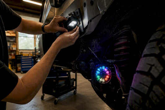 Hands installing rock and portal LED lights on vehicle frame