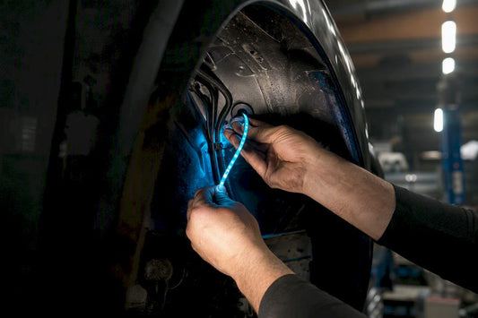 Hands routing car LED strip through wheel well