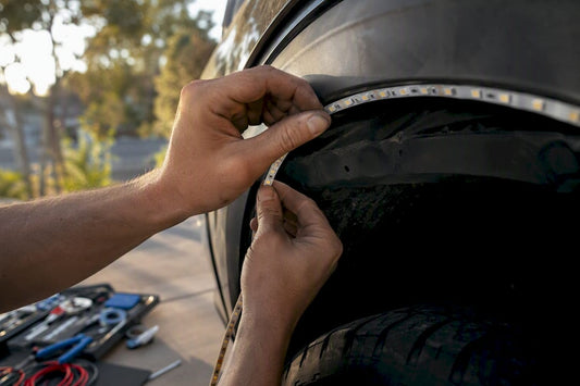 Hands installing LED strip in truck wheel well